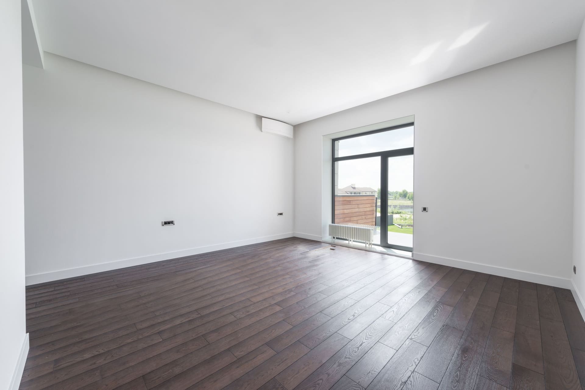 Besenreines, leeres Zimmer mit Parkettboden und Balkontür